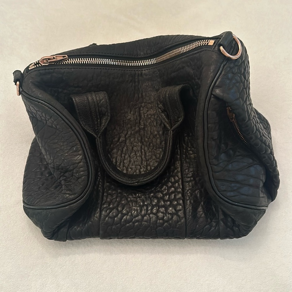 Black bag, rose gold zippers, rose gold bottom of bag with circle pegs.